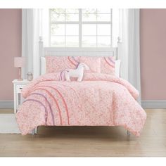 a pink and white bed with a unicorn on the comforter in front of a window