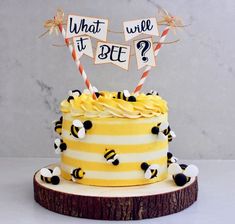 a yellow and white striped cake with honeybees on the top that says what it's bee?