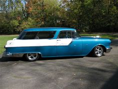 an old blue and white car parked in a parking lot