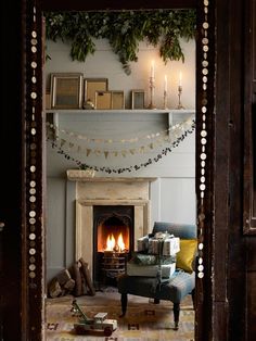 a living room filled with furniture and a fire place covered in christmas garlands next to a fireplace