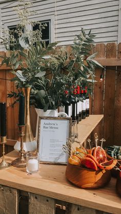 a wooden table topped with vases filled with flowers and fruit on top of it