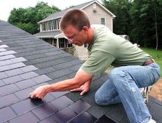 a man is working on the roof of his house while he fixes the shingles