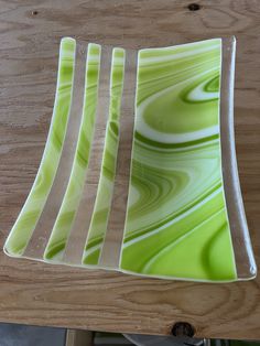 a green and white glass plate sitting on top of a wooden table next to a pair of scissors