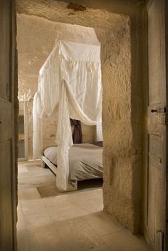 an open door leading to a bedroom with a white bed and canopy over the bed