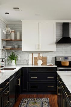 a kitchen with black and white cabinets, wood flooring and an area rug in the middle