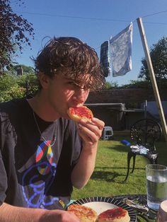 a young man eating pizza outside on a sunny day