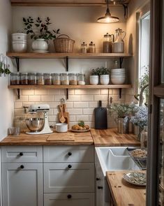 a kitchen filled with lots of wooden counter top next to white cabinets and shelves covered in pots