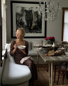 a woman sitting on a couch holding a bowl in her hands while eating food from a plate