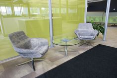 two chairs sitting next to each other in front of a glass wall with yellow walls