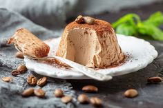 a piece of cake sitting on top of a white plate next to nuts and leaves