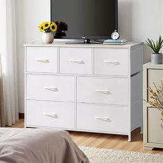 a flat screen tv sitting on top of a white dresser