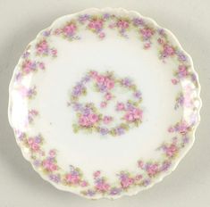 a white plate with pink and purple flowers on the rim that says c in it