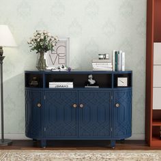 a blue cabinet sitting next to a lamp on top of a wooden floor in front of a book shelf