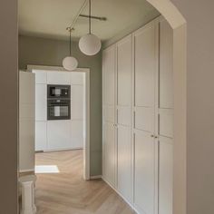 an empty room with white cabinets and wood floors