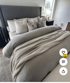 a large bed sitting in a bedroom next to a window with lots of pillows on top of it