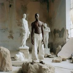 a man standing on top of a rock in front of some white marble statues and sculptures