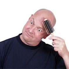 a bald man holding a hair brush over his head