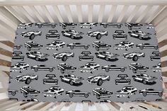 a baby crib with cars and trucks on it in black and white, as well as gray background