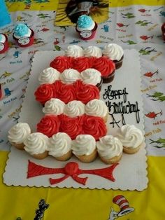 a table topped with cupcakes and a cake shaped like the number five on top of it