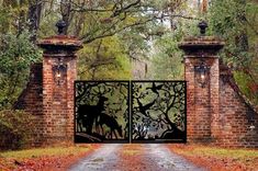 an iron gate with deer silhouettes on it in front of a brick wall and trees