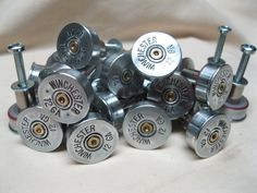 a pile of metal buttons and screws sitting on top of a white cloth covered table