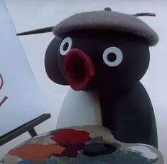 an animated penguin holding a paintbrush next to a painting easel with the word art written on it