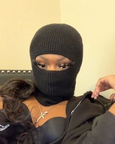 a woman wearing a black ski mask on top of her head and holding scissors in front of her face