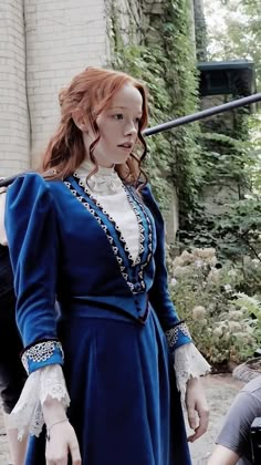 a woman with red hair wearing a blue dress