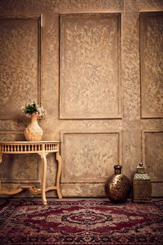 a room with a rug, table and vases on the floor next to it