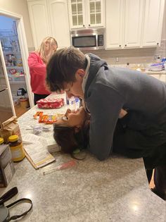 a man and woman kissing on the kitchen counter