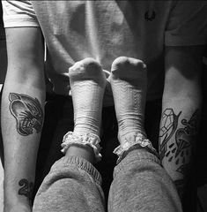 two people with tattoos on their legs sitting next to each other