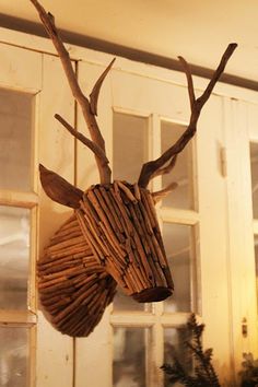 a wooden deer head hanging from the side of a wall in front of a window