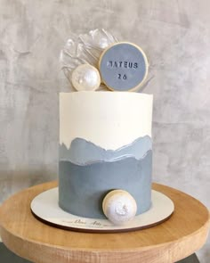 a blue and white cake on a wooden table with two balls in front of it