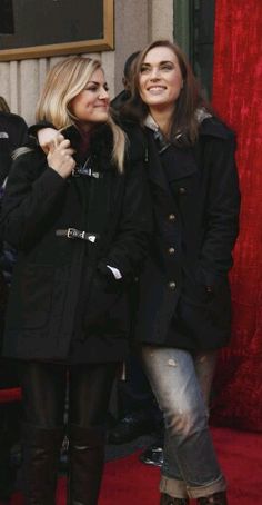 two women standing next to each other on a red carpet