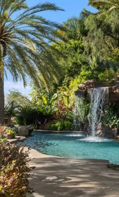 a pool with a waterfall surrounded by palm trees