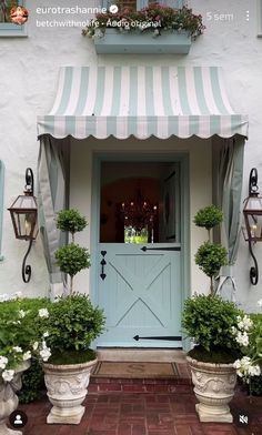 a blue front door with two planters on either side and an awning over it