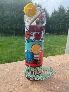 a plastic cup sitting on top of a stone wall with a straw in the bottom