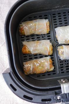 some food is being cooked in an air fryer with plastic wrappers on it