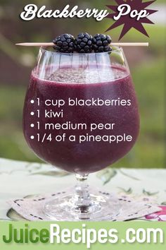 a glass filled with blackberries on top of a table