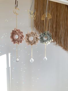 three different colored flowers are hanging from the ceiling in front of a white wall with fringes