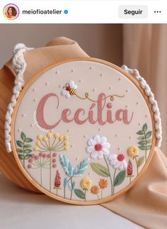 the embroidered name cecilia is displayed in front of a wooden frame with flowers on it