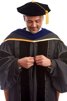 a man wearing a graduation gown and holding his hands on his chest while standing in front of a white background