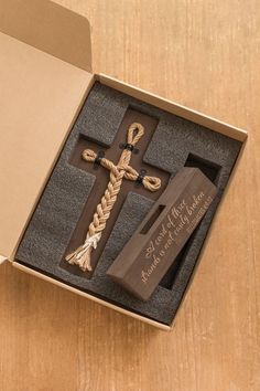 an open box with a wooden cross on the inside and roped in to it