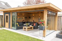 an outdoor living area with couches and tables in the center, surrounded by grass