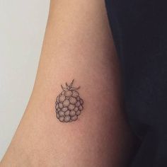 a black and white photo of a small tattoo on the arm that has grapes on it