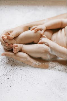 a woman holding a baby in her arms while she is being bathed by the water