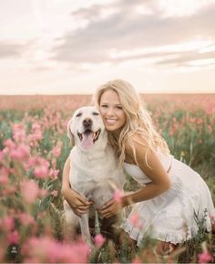 a woman is hugging her dog in the middle of a field full of pink flowers