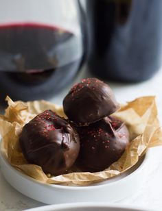 three chocolate covered donuts in a white bowl