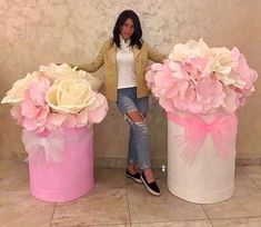 a woman standing next to two large pink vases with flowers in them and the caption fortuna decor