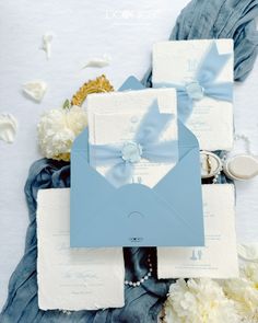 a blue and white wedding stationery with flowers on the side, including an envelope